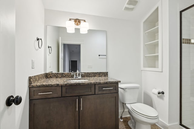 bathroom with a shower with door, vanity, and toilet