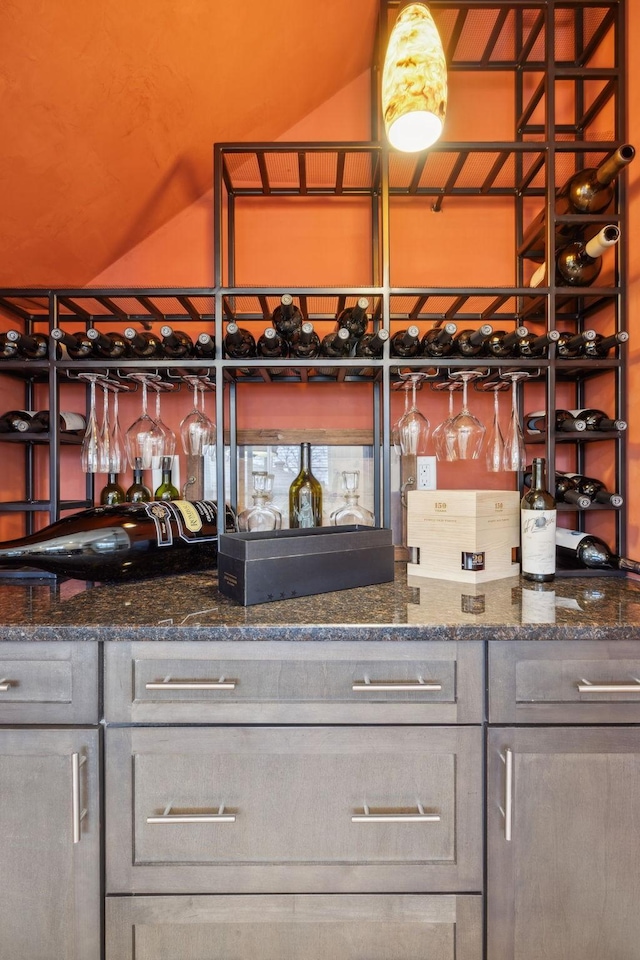 interior space with lofted ceiling, gray cabinets, and dark stone counters