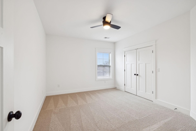 unfurnished bedroom featuring light colored carpet, ceiling fan, and a closet