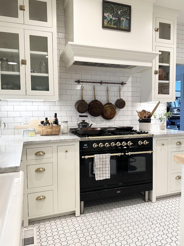 kitchen featuring white cabinetry, double oven range, light stone countertops, and decorative backsplash