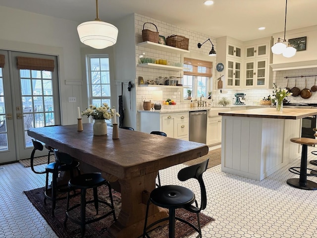 kitchen featuring a kitchen island, pendant lighting, tasteful backsplash, white cabinets, and stainless steel dishwasher