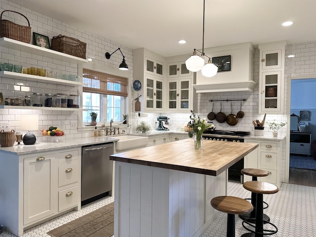 kitchen with pendant lighting, sink, white cabinets, a center island, and stainless steel dishwasher