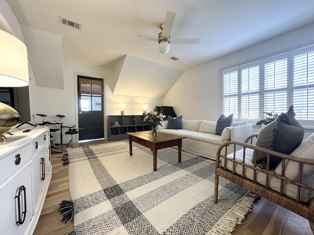 living room with ceiling fan, vaulted ceiling, and light hardwood / wood-style flooring