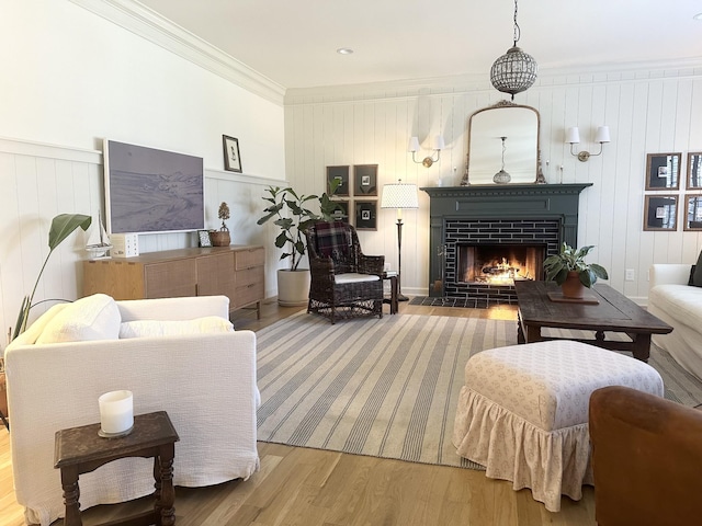 living room with ornamental molding, wood-type flooring, and a brick fireplace