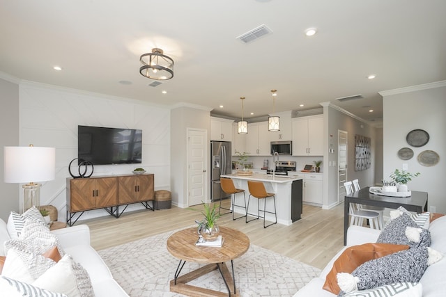 living room with sink, crown molding, and light hardwood / wood-style floors