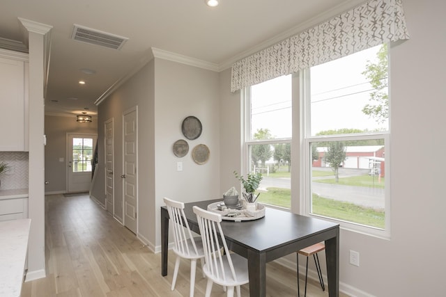 dining space featuring ornamental molding and light wood-type flooring