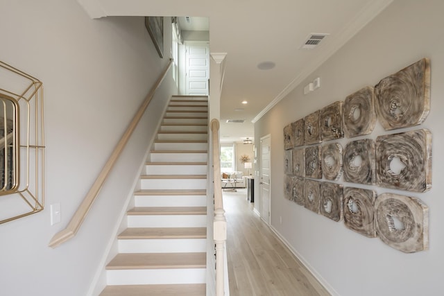 stairs featuring hardwood / wood-style flooring and ornamental molding