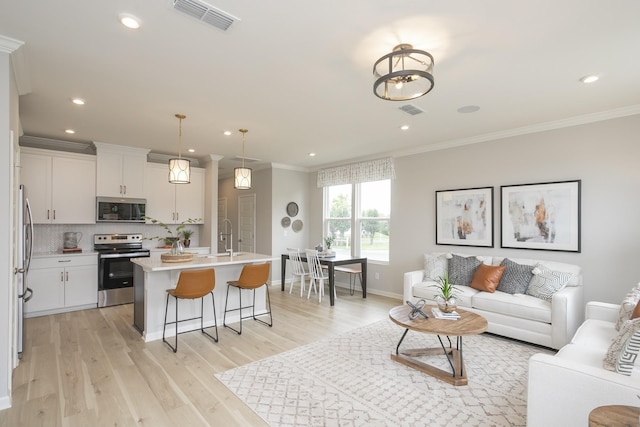 living room with ornamental molding, sink, and light hardwood / wood-style flooring