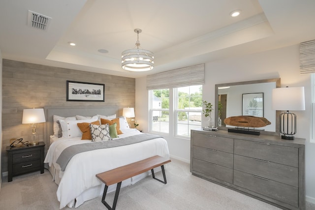 bedroom with a tray ceiling, light colored carpet, and a chandelier