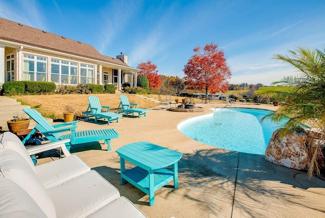 view of pool featuring a patio and an outdoor living space with a fire pit