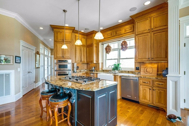 kitchen with appliances with stainless steel finishes, pendant lighting, sink, a center island, and light stone counters