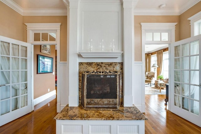 interior space with a high end fireplace, ornamental molding, light hardwood / wood-style floors, and french doors