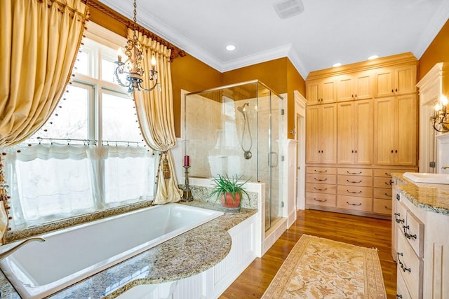 bathroom featuring hardwood / wood-style flooring, crown molding, vanity, and plus walk in shower