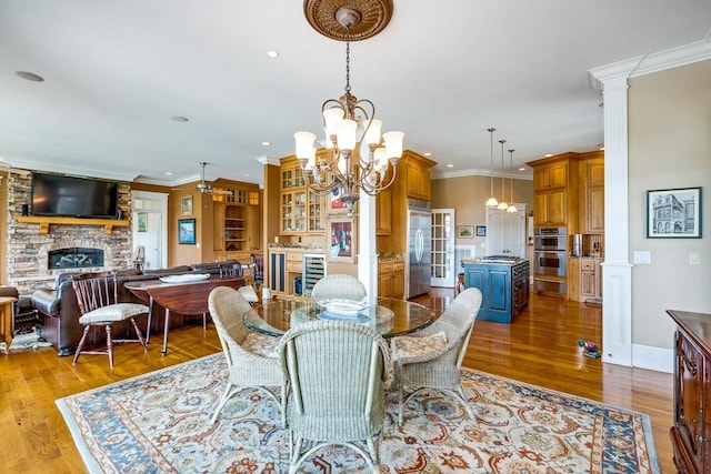 dining space with crown molding, a fireplace, and light hardwood / wood-style floors