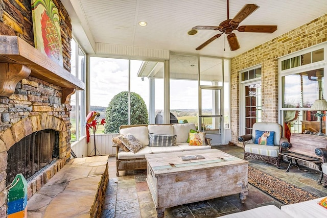 sunroom / solarium featuring ceiling fan and a fireplace