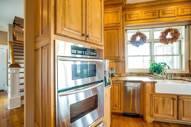 kitchen featuring double oven, dark wood-type flooring, light stone countertops, and sink