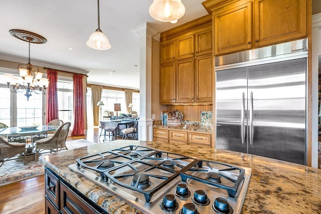 kitchen featuring light stone counters, hanging light fixtures, stainless steel appliances, and light hardwood / wood-style floors