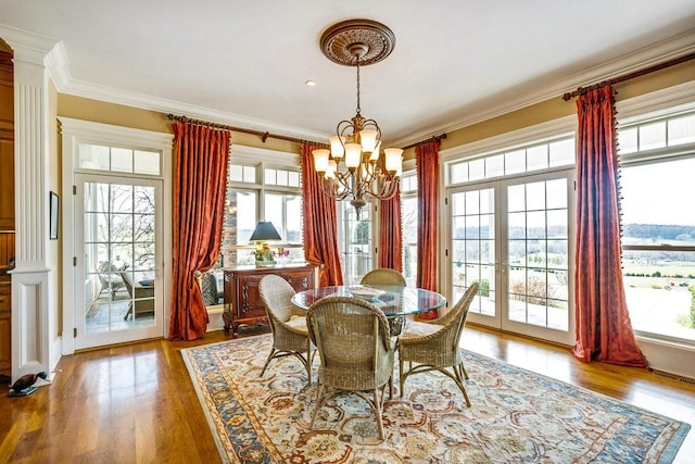 dining room with french doors, ornamental molding, a chandelier, and hardwood / wood-style floors