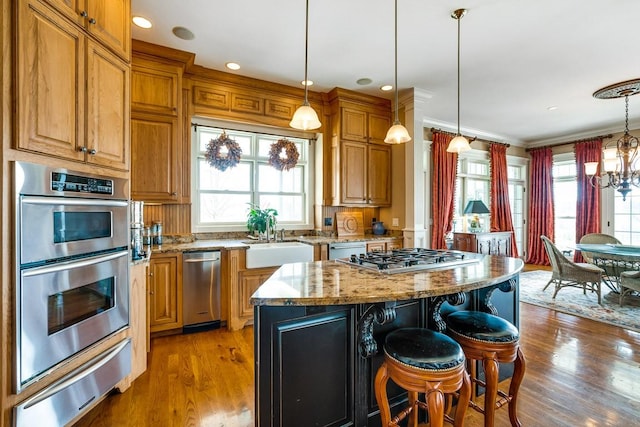 kitchen featuring sink, light stone countertops, a center island, and appliances with stainless steel finishes