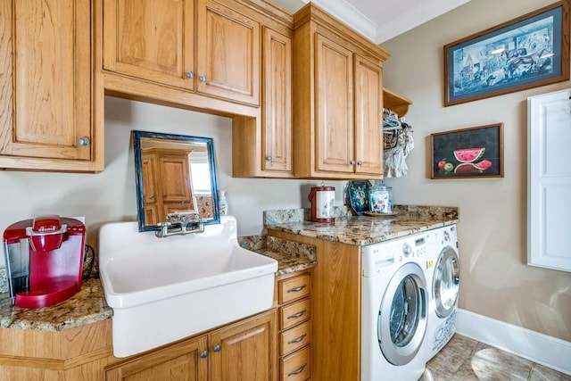 clothes washing area with crown molding, cabinets, sink, and washing machine and clothes dryer