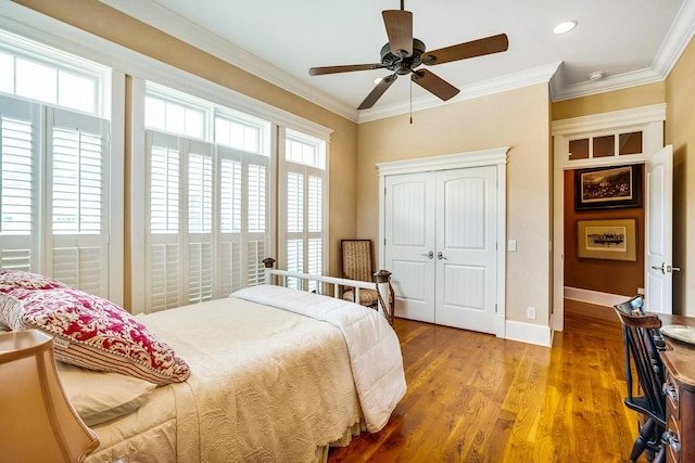 bedroom with crown molding, ceiling fan, light wood-type flooring, and a closet