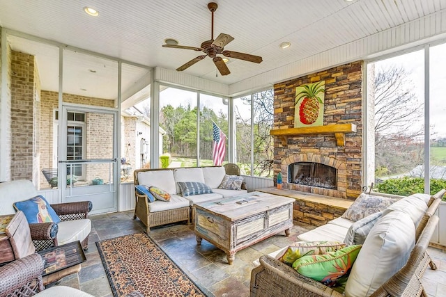 sunroom with a stone fireplace and ceiling fan