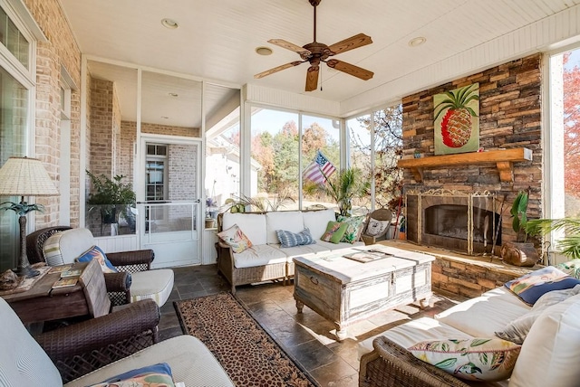 sunroom / solarium featuring ceiling fan and an outdoor stone fireplace