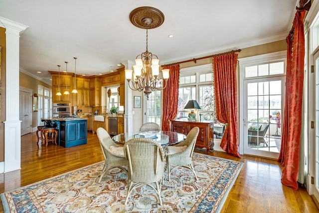 dining room with a notable chandelier, light hardwood / wood-style flooring, ornamental molding, and ornate columns