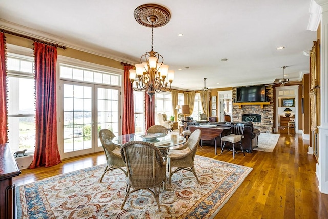 dining area featuring crown molding, a fireplace, ceiling fan with notable chandelier, and hardwood / wood-style flooring