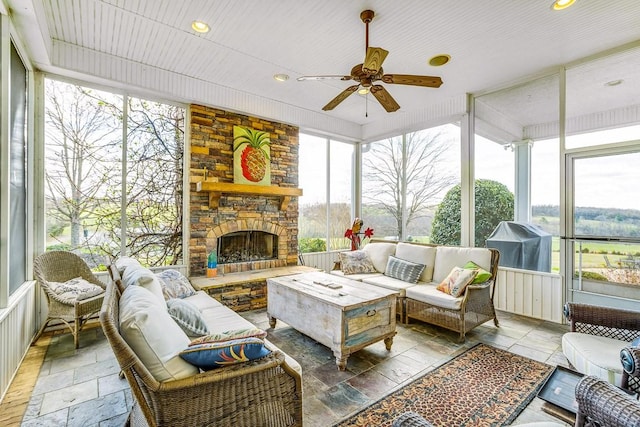 sunroom / solarium featuring ceiling fan, a fireplace, and a healthy amount of sunlight