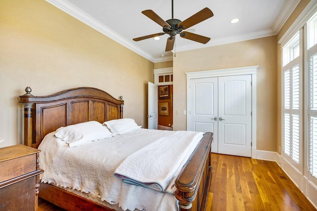 bedroom with wood-type flooring, ornamental molding, ceiling fan, and a closet