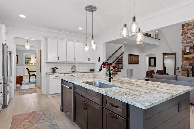 kitchen with white cabinetry, sink, and an island with sink