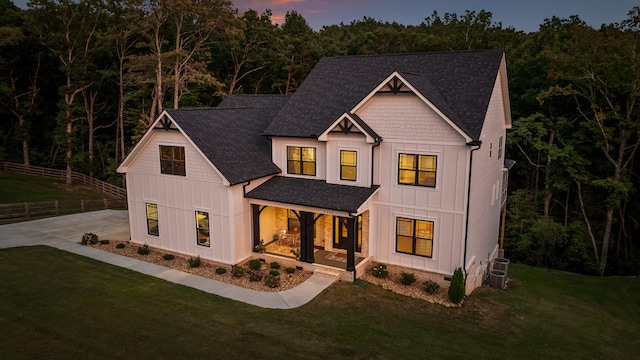 modern farmhouse style home with a lawn, central air condition unit, and covered porch