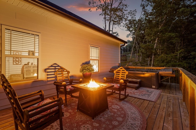 deck at dusk featuring a hot tub and an outdoor fire pit