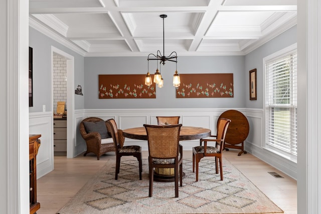 dining area with an inviting chandelier, coffered ceiling, light hardwood / wood-style flooring, and beamed ceiling