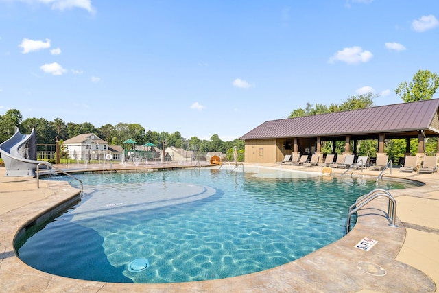 view of pool with a water slide and a patio area