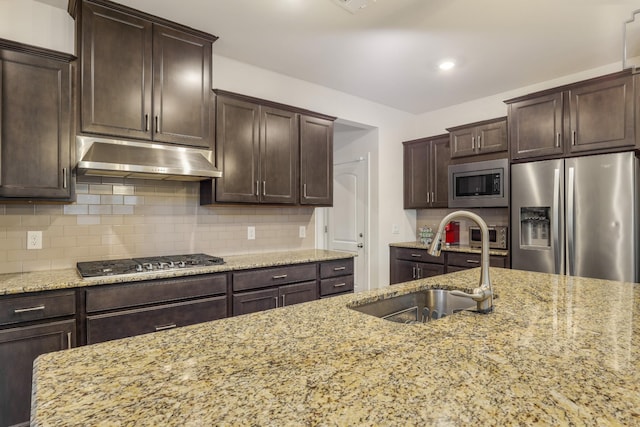 kitchen with light stone counters, sink, tasteful backsplash, and stainless steel appliances