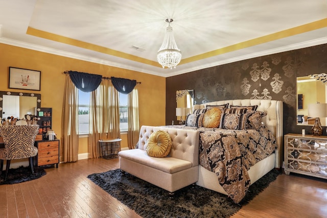 bedroom with an inviting chandelier, hardwood / wood-style flooring, ornamental molding, and a raised ceiling