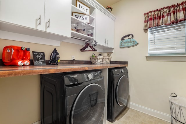 clothes washing area with cabinets and washing machine and clothes dryer