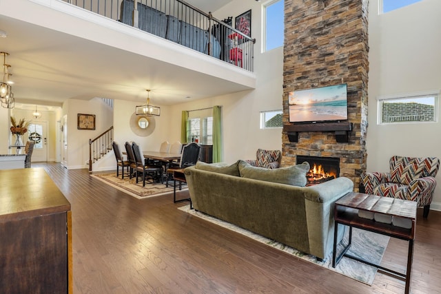 living room with a high ceiling, dark hardwood / wood-style floors, a fireplace, and an inviting chandelier