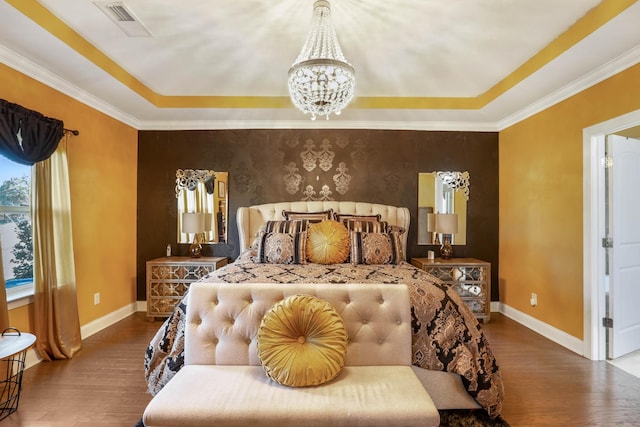 bedroom with hardwood / wood-style floors, a notable chandelier, and a tray ceiling