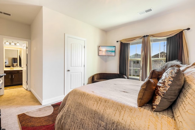 bedroom featuring ensuite bath and light colored carpet