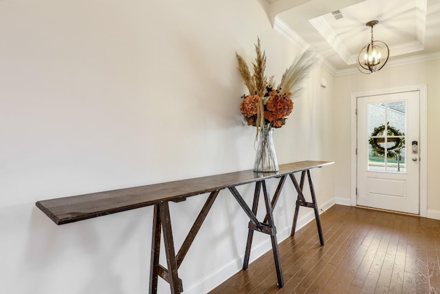 entryway featuring ornamental molding, dark hardwood / wood-style flooring, a chandelier, and a tray ceiling