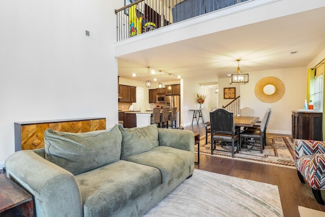 living room featuring dark hardwood / wood-style flooring, a chandelier, and a high ceiling