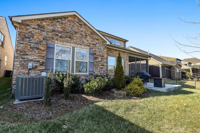 rear view of property featuring a lawn and central air condition unit