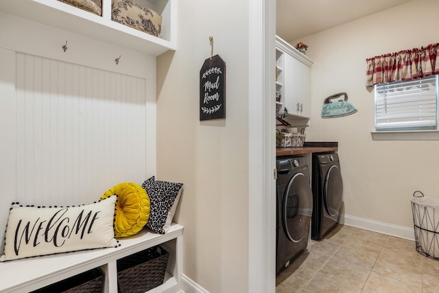 washroom with cabinets, washing machine and clothes dryer, and light tile patterned floors