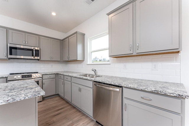 kitchen featuring gray cabinets, light stone countertops, and appliances with stainless steel finishes