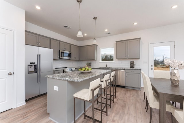 kitchen featuring gray cabinetry, hanging light fixtures, stainless steel appliances, and a center island