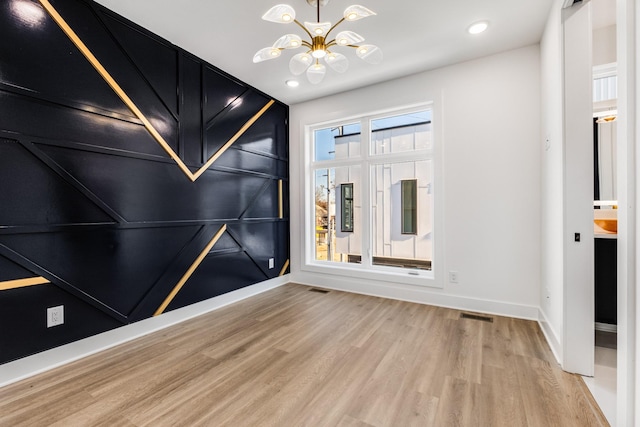 empty room featuring an inviting chandelier and hardwood / wood-style floors