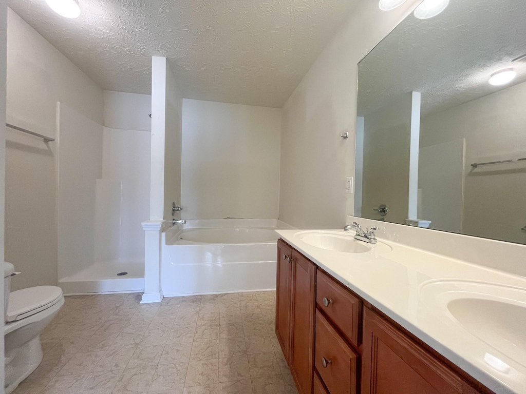 full bathroom featuring vanity, toilet, a textured ceiling, and plus walk in shower